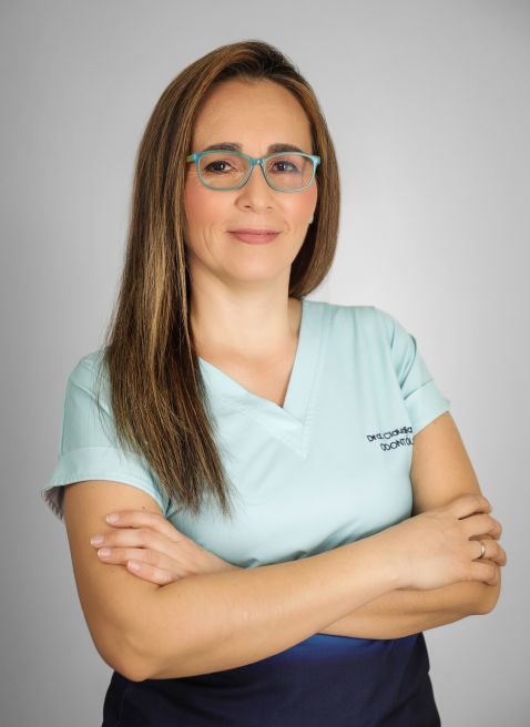Paciente en consulta odontológica, con brackets, siendo revisada por un dentista con guantes azules y herramientas dentales.