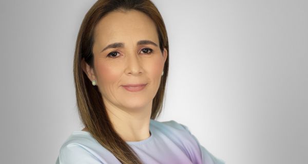 Mujer joven sonriendo durante una revisión dental, atendida por dos profesionales con guantes blancos y herramientas odontológicas.