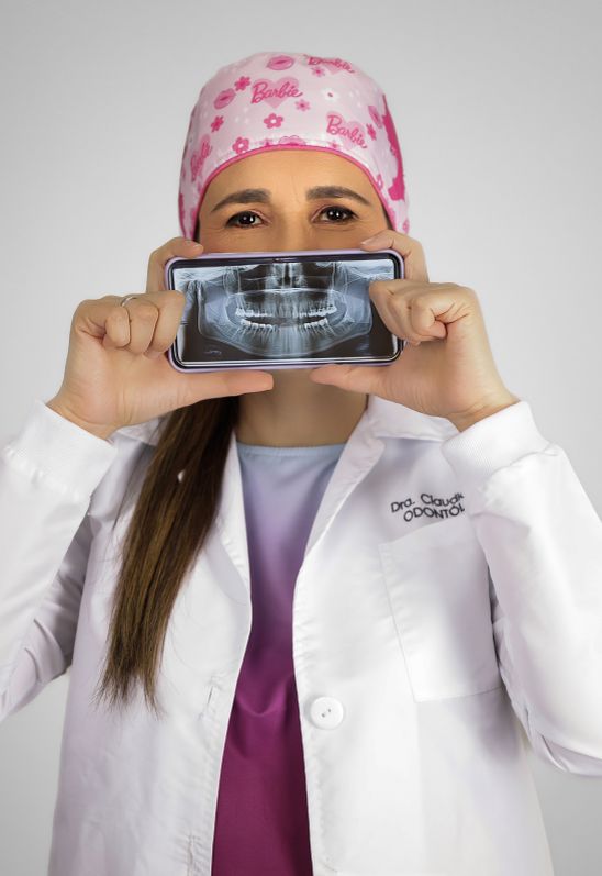 Vista desde el interior de una boca hacia un dentista que examina con herramientas dentales, usando mascarilla, guantes, gafas protectoras y gorro quirúrgico colorido